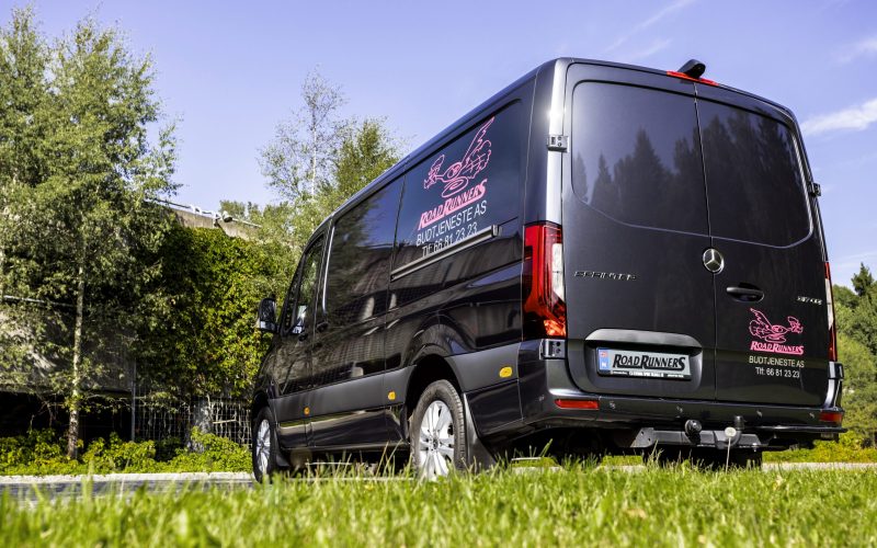 Baksiden av en mørk budbil med Road Runners logen bak og på siden.