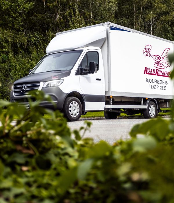 Hvit budbil med en Road Runners logoen på siden.