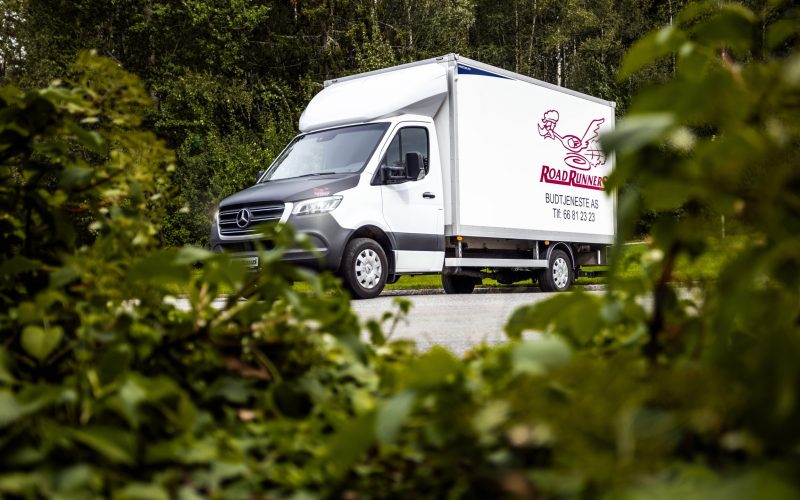 Hvit budbil med en Road Runners logoen på siden.
